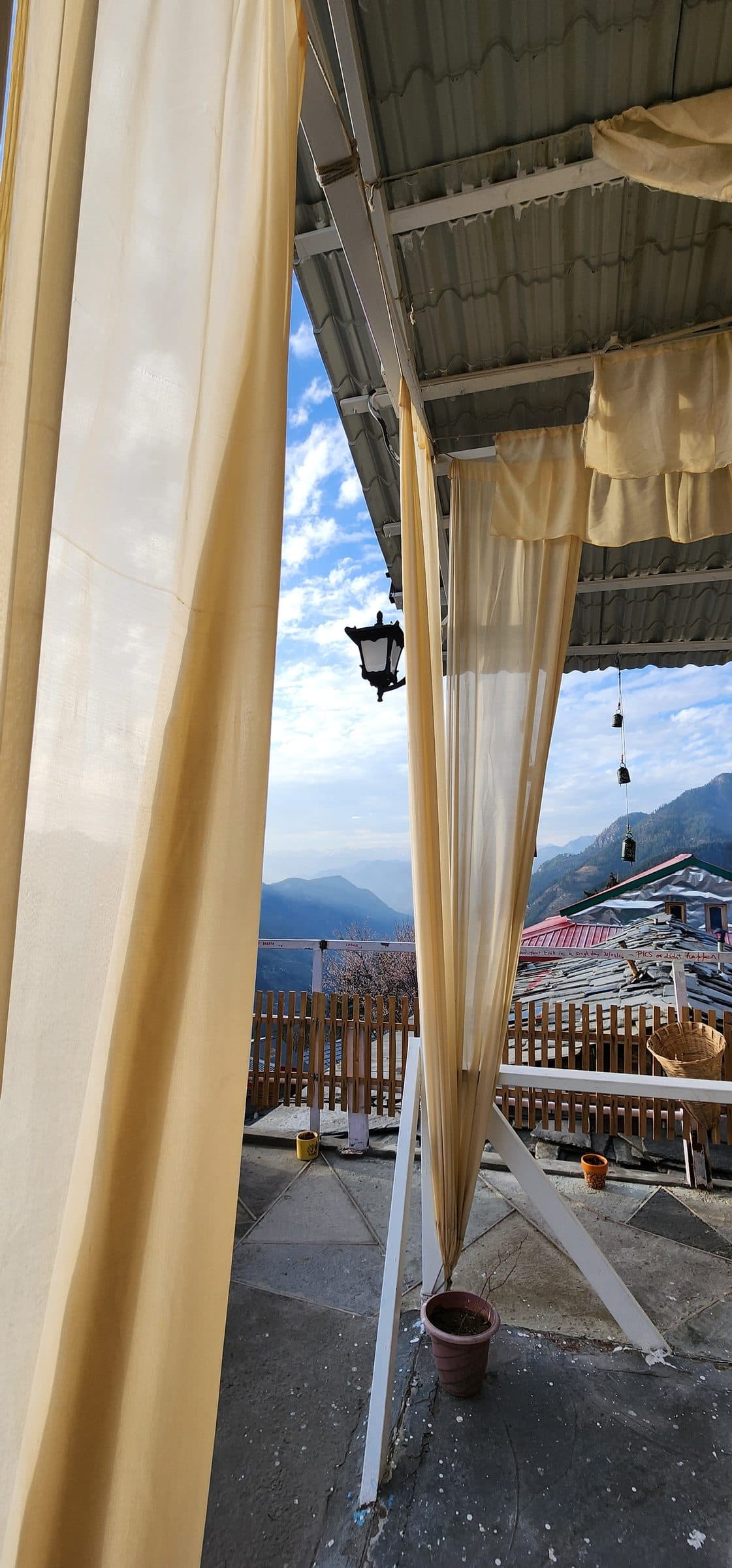 Yellow curtains frame a view of distant mountains and sky