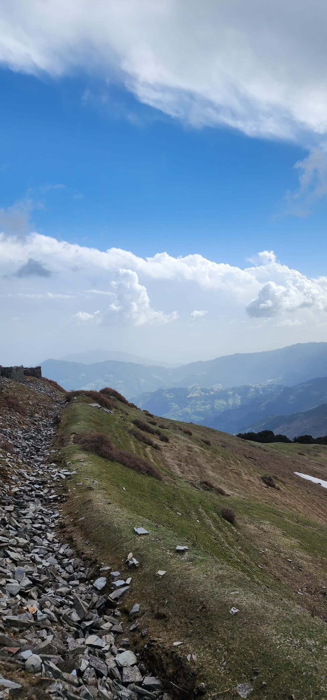 A panoramic view of a lush green mountain trail in Jibhi Valley, Himachal Pradesh, India.