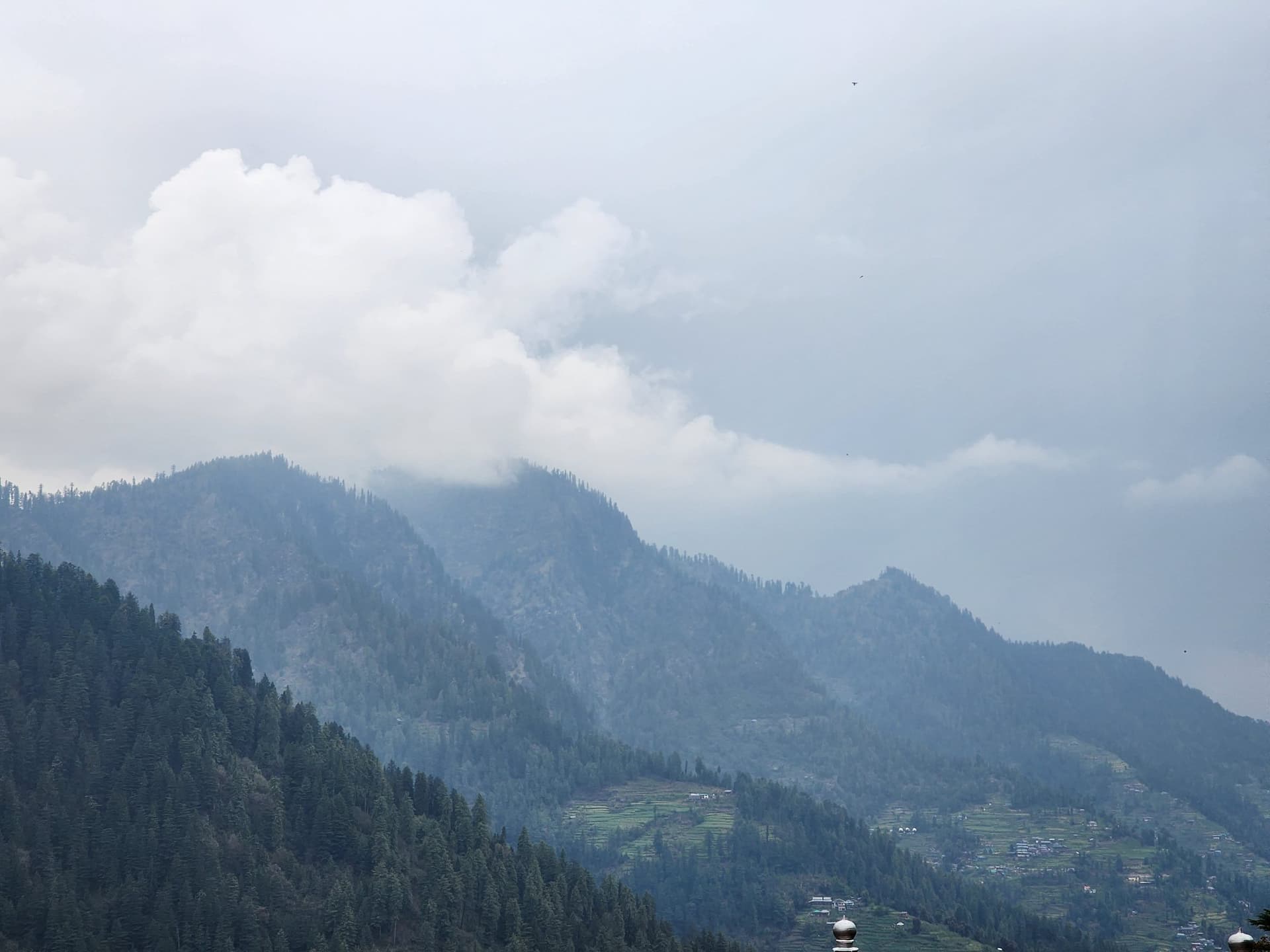 Rolling green mountains covered in dense forest under a cloudy sky