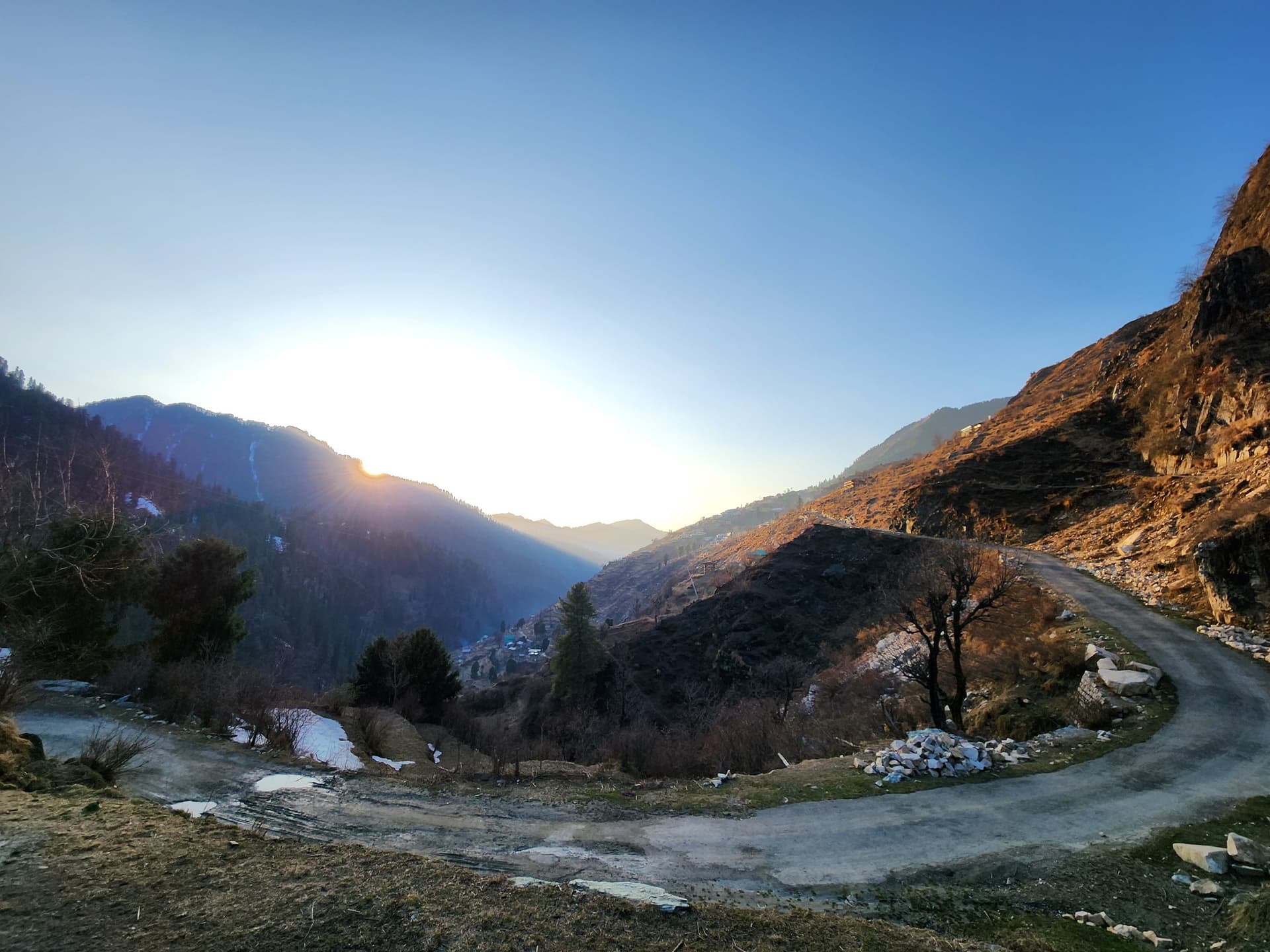 Dirt road winding through dry, sloping hills in the Himachal Pradesh valley