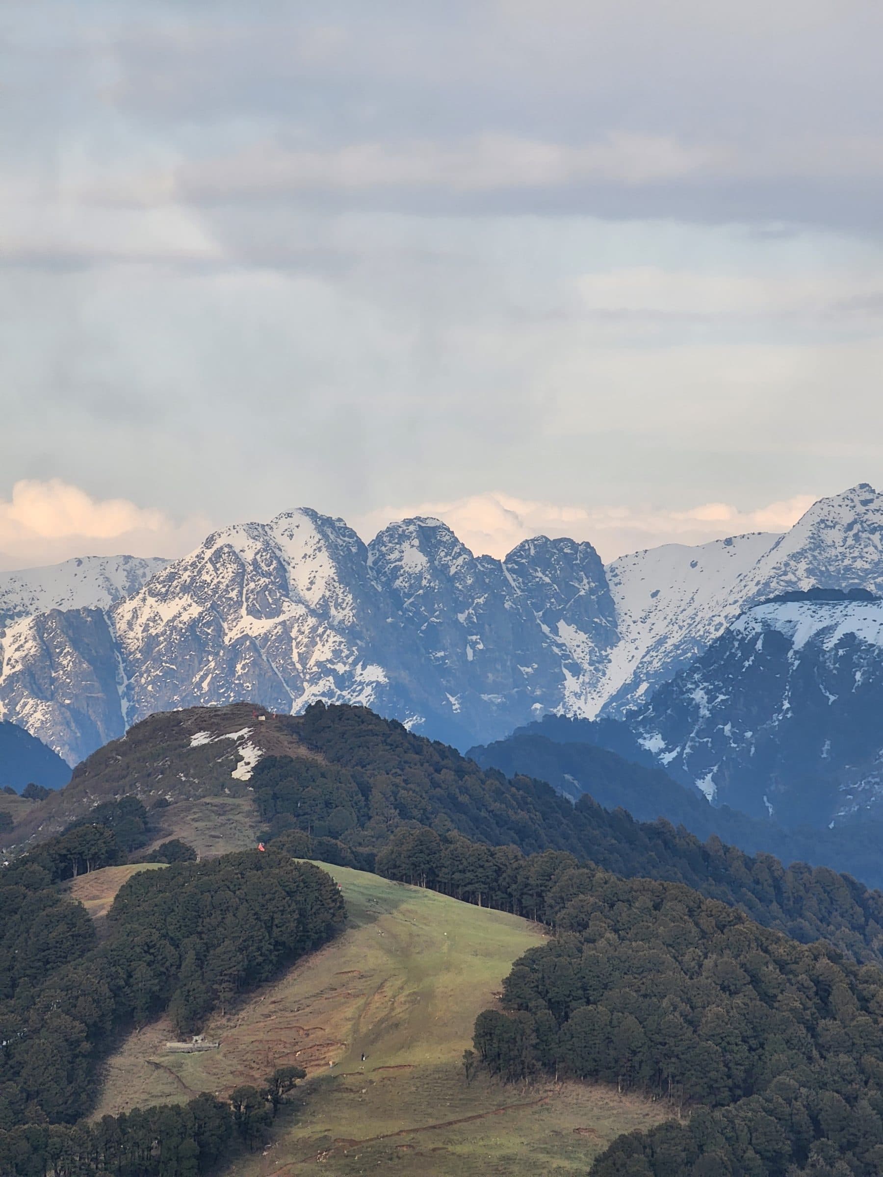 Rolling green forested hills leading up to distant mountains under a misty sky, from Raghupur Fort