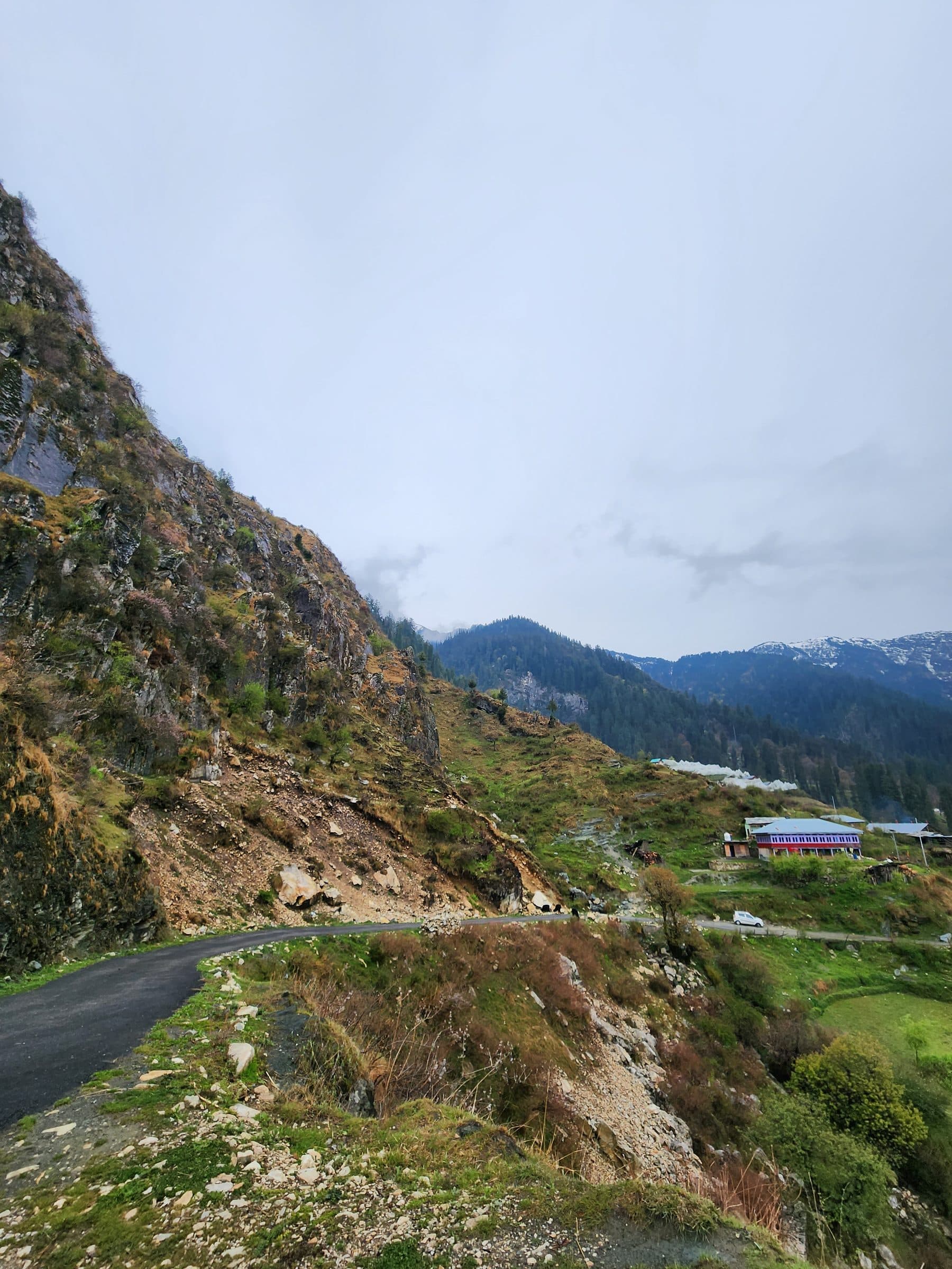Rocky mountain slope with a winding road under cloudy sky