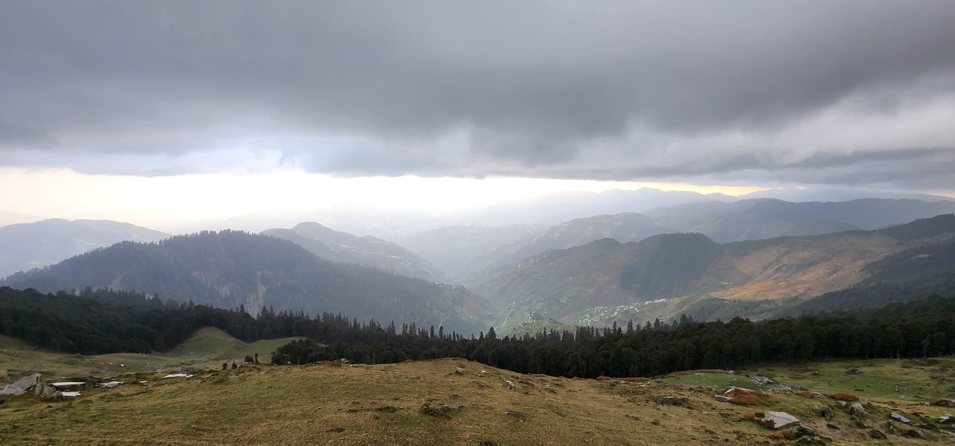 Rolling, forested hills in Jibhi Valley covered by heavy mist and fog