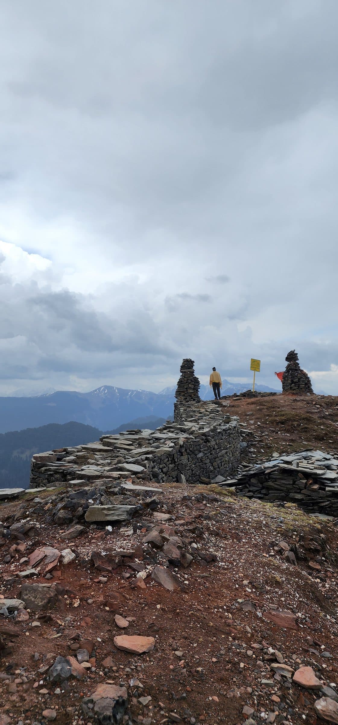 Person standing among large rocks overlooking a misty mountain valley