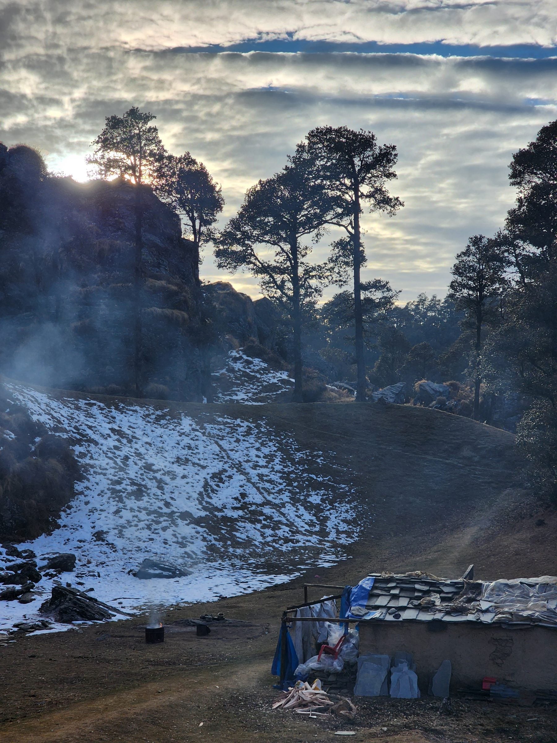 Evening Glow Amidst Jibhi Valley's Rustic Charm A cozy scene featuring a bonfire amidst a rocky hillside in Jibhi Valley, Himachal Pradesh, India.