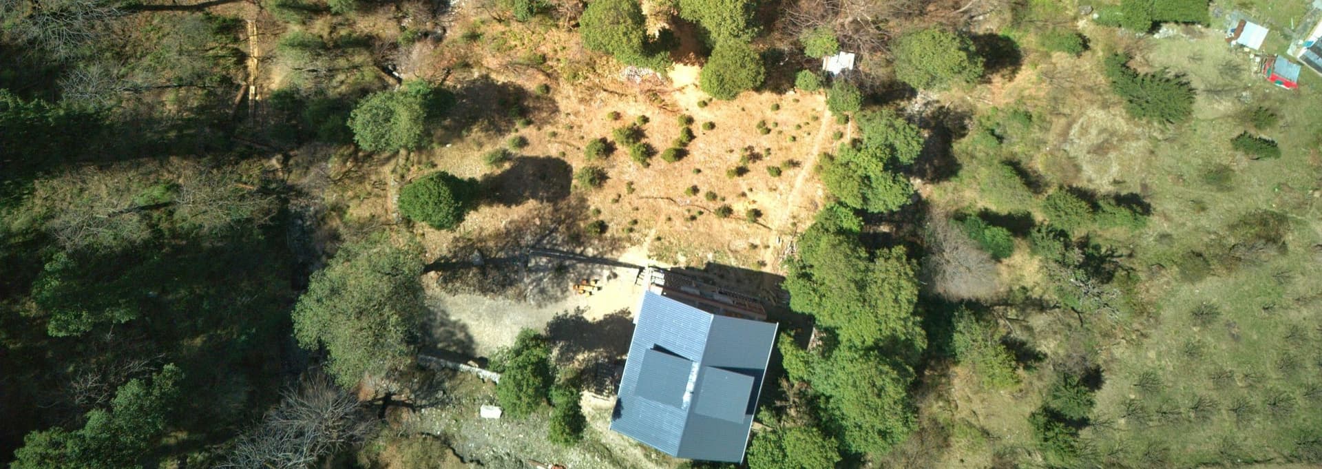 Ailyak Shoja - Nesteled within forest with a stream nearby