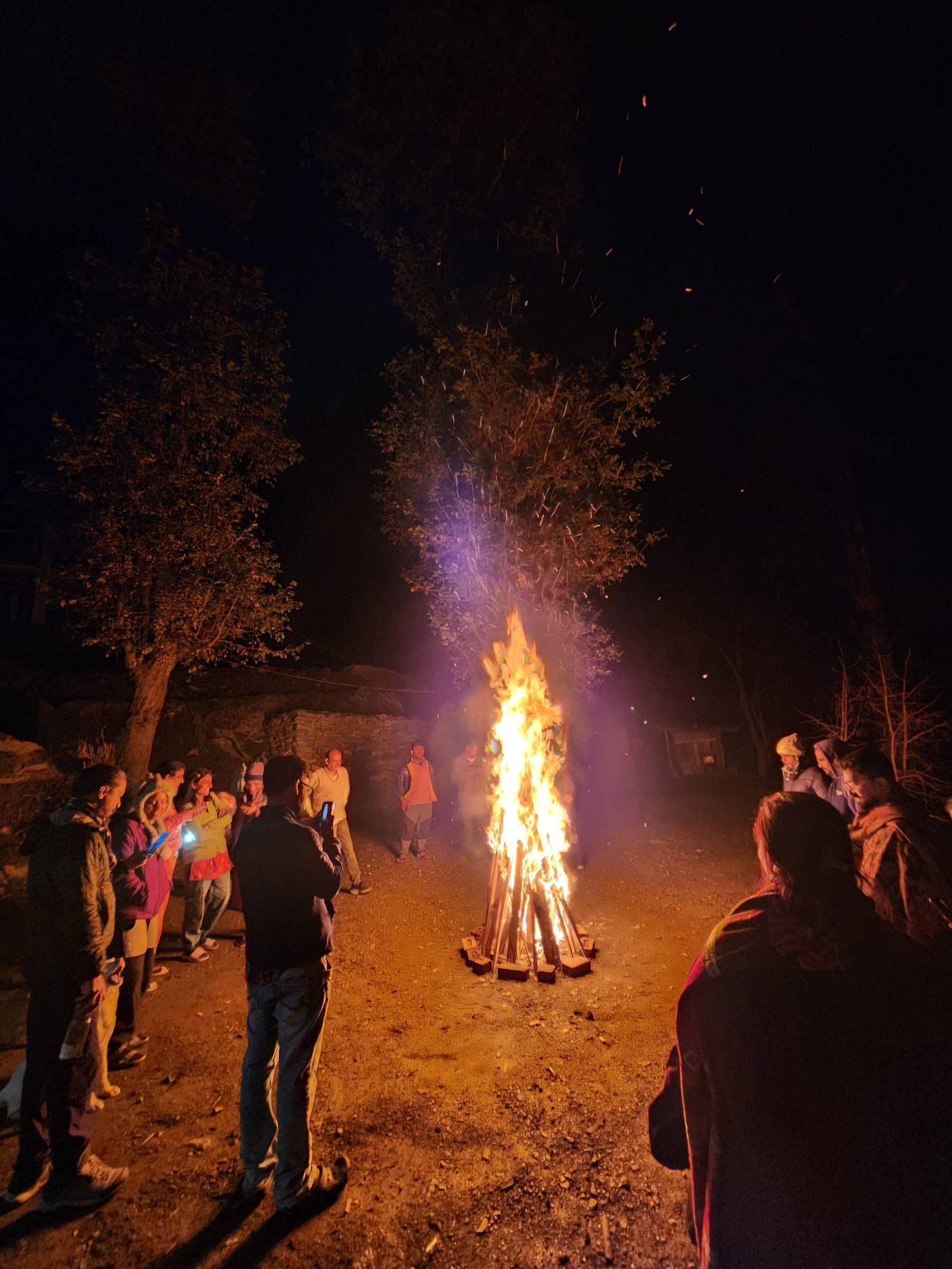 Jibhi Valley: Warmth Under Starry Skies Group of people watching a crackling bonfire in the foothills of Jibhi Valley, Himachal Pradesh.