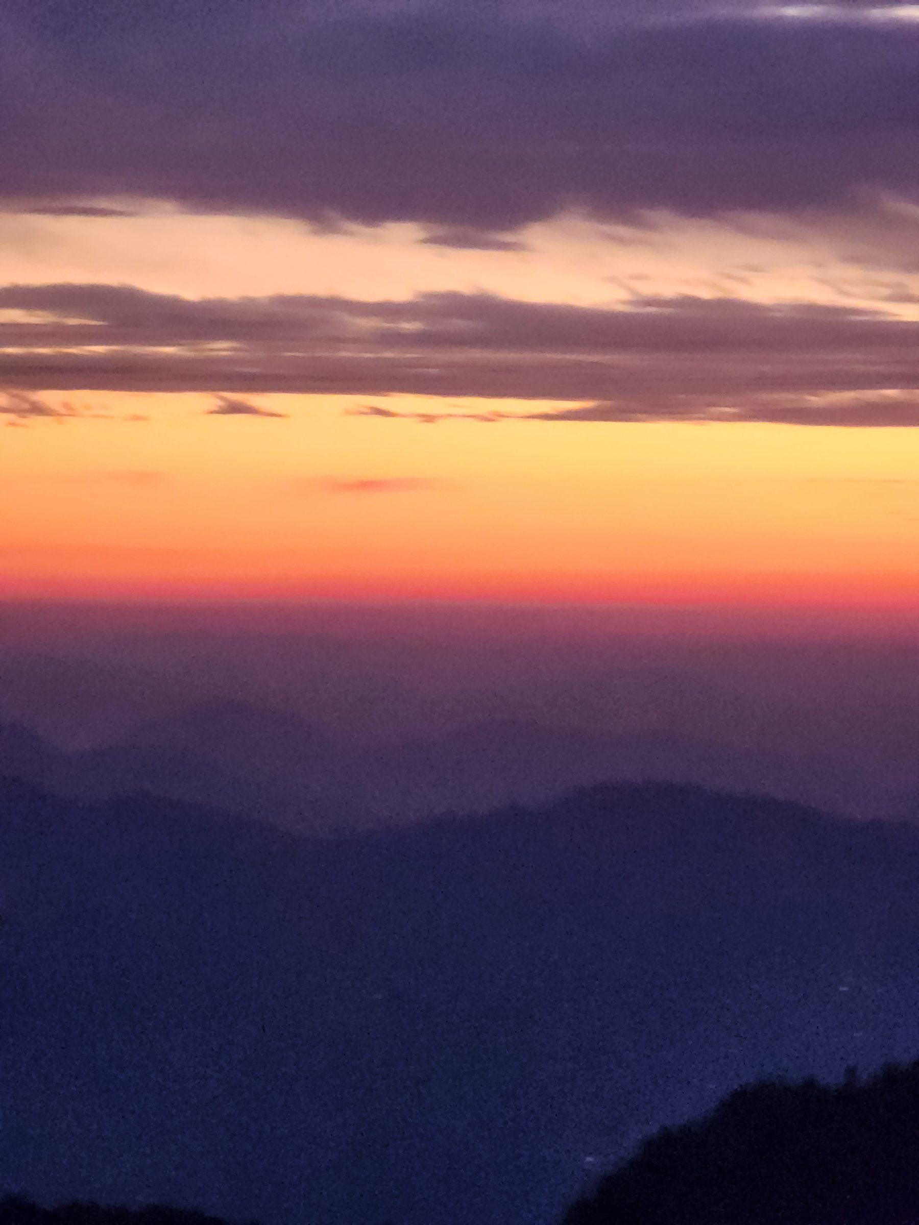 Layered mountain silhouettes and colorful sky over the Jibhi Valley landscape