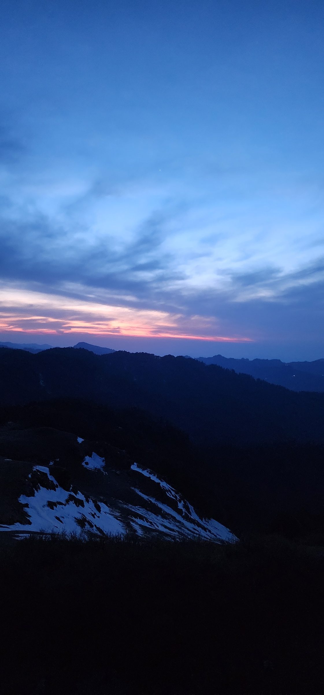 Dark silhouette of rolling hills and sky with soft clouds